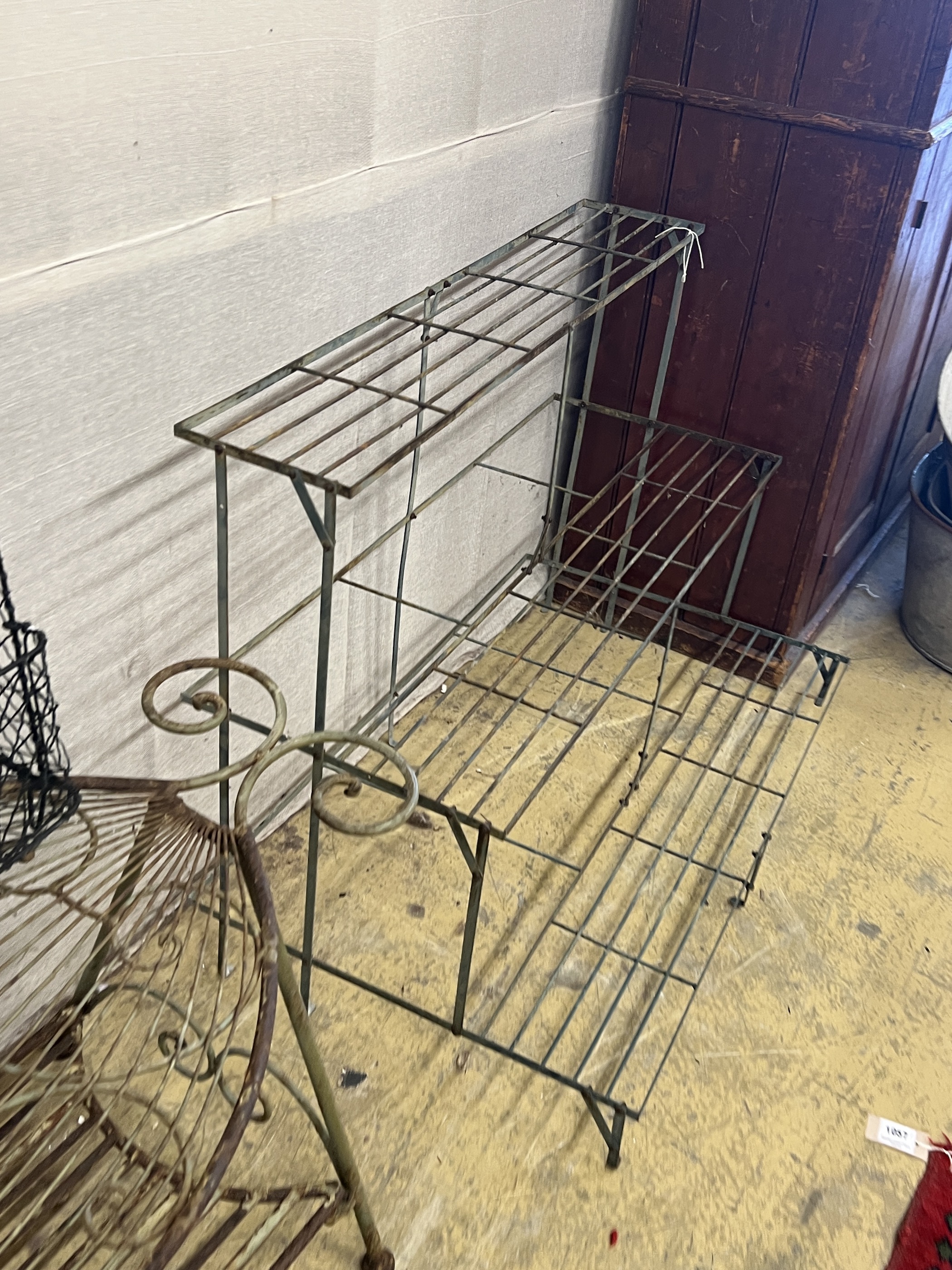 A painted wrought iron three tier pot stand, width 100cm, together with an oval wrought iron garden table and a three tier rack